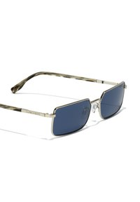 Lunettes de soleil rectangulaires avec un cadre en métal argenté et des verres bleus. Motif écaille sur les branches. Comprend des plaquettes de nez ajustables.