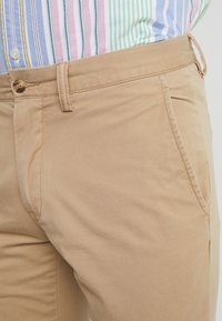 Beige katoenen broek met een rechte snit. Voorzien van een knoopsluiting, zijzakken en een soepele textuur. Casual ontwerp dat geschikt is voor verschillende gelegenheden.