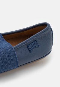 Niebieskie buty wsuwane z teksturowanym elastycznym paskiem i gładką skórzaną cholewką, z logo marki Camper po boku.