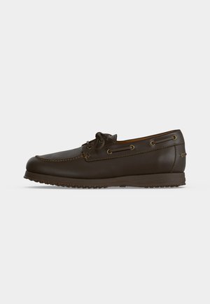 Dunkelbrauner Leder-Bootsschuh mit Schnürdetail, Moc-Toe-Naht, Gummisohle und seitlichen Ösen auf einem einfarbigen hellen Hintergrund.