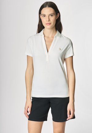 Polo shirt bianco con maniche corte e scollo a V, dotato di un piccolo logo sul lato sinistro del petto. Indossato con pantaloni corti neri, il modello si staglia su uno sfondo chiaro.