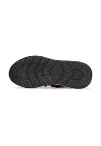 Semelle en caoutchouc noir avec un motif texturé ; présente des formes géométriques surélevées et des rainures pour l'adhérence ; matériau marron sur le bord supérieur.