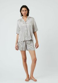 Grå pyjamas sæt med korte ærmer, bestående af en skjorte med knapper og matchende shorts. Har et diskret palmeblad mønster og glat, skinnende stof.
