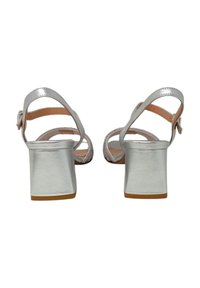 Sandali con tacco alto argentati, con tacco spesso, cinghie con accenti scintillanti e una finitura metallica liscia. Presentano una chiusura a fibbia.