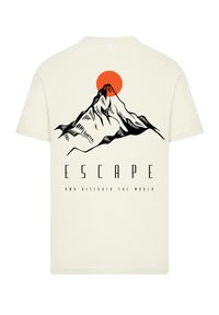 Cream-colored t-shirt featuring a black mountain illustration, an orange sun, and "ESCAPE AND DISCOVER THE WORLD" text in bold font.