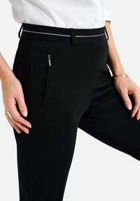 Zwarte broek met een gladde textuur, voorzien van een zijritszak, een dunne contrasterende tailleband en een getailleerde pasvorm voor een slanke uitstraling.