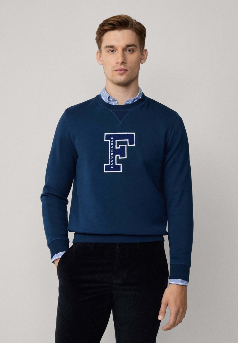 Felpa blu navy realizzata in morbido tessuto, con una lettera "F" ricamata di colore bianco e la parola "FACONNABLE" sottostante, con polsini a costine.