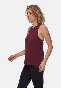 Bordeaux ärmlös sporttop med rund halsringning och sidofodringar, gjord av mjukt, lätt material, med en liten logotypdetalj.