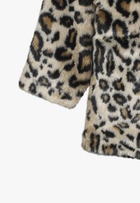 Tela de piel sintética con estampado de leopardo, con manchas beige, negras y marrones, mostrando una porción de una manga y el borde de la prenda.