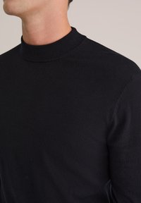 Pulover negru cu guler înalt, design mulat, textură moale, guler ribbed și material neted cu cusături minime. Potrivit pentru stratificare.