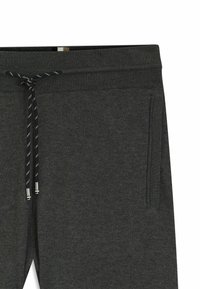 Ciemnoszare spodnie dresowe z prążkowanym pasem, regulowanym sznurkiem i bocznymi kieszeniami. Materiał wydaje się miękki o gładkiej fakturze.