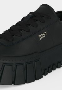 Μαύρο platform sneaker με χοντρή, εξογκωμένη σόλα, μαύρα κορδόνια και λογότυπο "tommy jeans" στην πλευρική επιφάνεια.