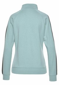 Hellblaues Sweatshirt mit hohem Kragen, Raglanärmeln und schwarzen Seitenstreifen. Weiches Material mit strukturierter Oberfläche.