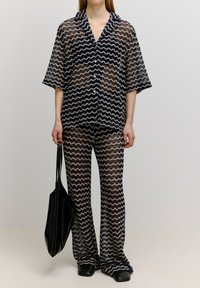 Zweiteiliges Outfit mit einem lockeren, kurzärmeligen Hemd mit Knopfleiste und passenden, auslaufenden Hosen in einem marineblauen und cremefarbenen Zickzackmuster, gefertigt aus transparenter Stoff.