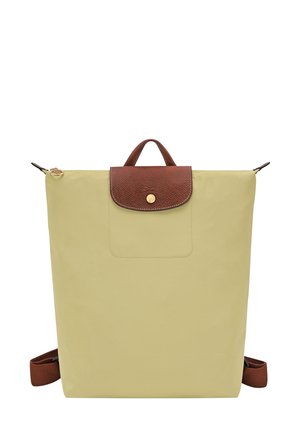 Light yellow backpack with a textured brown top flap, gold hardware, a front pocket, and adjustable brown straps. Compact rectangular shape.
