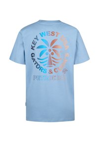 Světle modré bavlněné tričko s kulatým grafickým designem, který zobrazuje palmovi, text "Key West USA" a barevné akcenty v oranžové, modré a černé.