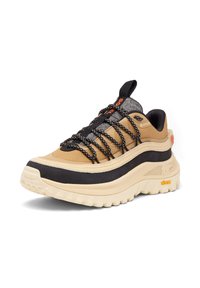 Beige ja mustad tossud, millel on paks tald, tekstureeritud ülemine osa ja mitmevärvilised nöörid. Omab silmapaistvat logo ja Vibram brändimist taldadel.