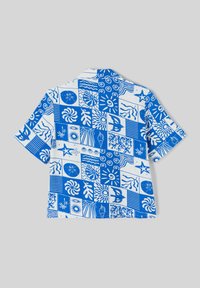 Chemise à manches courtes avec un motif patchwork bleu et blanc, mettant en avant divers motifs océaniques et floraux. Tissu en coton, coupe décontractée.