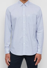 Camicia azzurro chiaro in cotone a scacchi, con maniche lunghe, tasca e colletto classico.