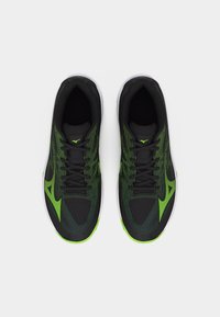 Ζευγάρι μαύρα και πράσινα παπούτσια για τρέξιμο με κορδόνια, που βλέπονται από πάνω σε λευκό φόντο.