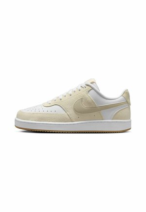 Beige and white sneaker with a textured upper, smooth leather accents, perforated toe, and a rubber outsole. Features a small logo near the heel.