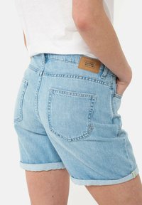 Lichtblauwe denim shorts met omgerolde zomen, twee achterzakken en een bruine label op de tailleband met de branding "Camel Active".