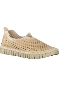 Scarpe slip-on di colore beige chiaro realizzate in materiale flessibile, con una tomaia decorata, fori per la traspirabilità e suola in gomma texturizzata.