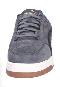 Sneaker in suede grigio con una suola intermedia bianca e suola in gomma. Presenta un design con lacci, punta perforata e dettagli del logo sul lato.