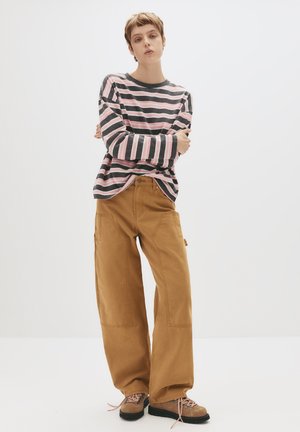 Gestreiftes Langarmhemd in Grau und Rosa, kombiniert mit beigen, weit geschnittenen Hosen. Braune Schnürschuhe. Einfaches, lässiges Design.