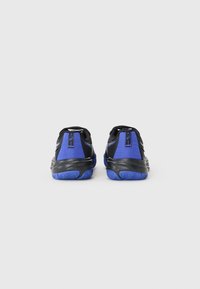 Baskets de sport noires et bleues avec une tige texturée, un col rembourré et une semelle à motifs. Présente un fini lisse et des accents contrastants.