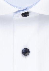 Weißes Hemd mit zwei schwarzen Knöpfen auf der Vorderseite und hellblauem inneren Kragenbesatz, der einen Teil der Knopfleiste zeigt.