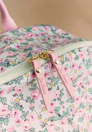 Prim-plan al unei genți cu model floral, cu bride roz pentru fermoar și accesorii aurii pentru fermoar, evidențiind detaliile țesăturii și designului.