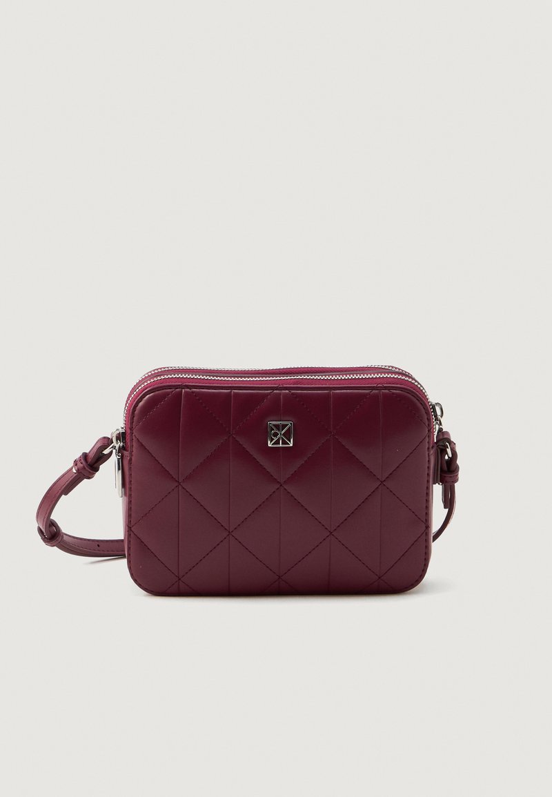 Geantă acoladă de culoare burgundă, fabricată dintr-un material lucios, cu un accent al logo-ului argintiu, închidere cu fermoar și o curea ajustabilă. Design compact, de formă rectangulară.