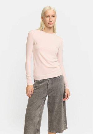 Lichtroze longsleeve top gemaakt van zachte stof, met een aangesloten pasvorm. Gecombineerd met grijze wijde broek met een relaxte snit en subtiele textuur.
