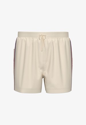 Costume da bagno beige con vita elasticizzata, coulisse frontale, strisce laterali in rosso, bianco e blu, e marchio Calvin Klein lungo i lati.