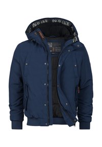 Chaqueta acolchada de color azul marino con capucha, que presenta un cierre de cremallera, bolsillos laterales y puños de canalé. Forrada con tela negra y con detalles de marca.