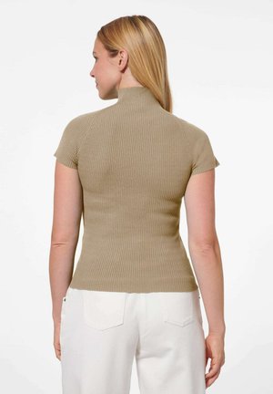 Beige, eng anliegendes Oberteil mit kurzen Ärmeln aus geripptem Strick, das einen hohen Kragen und eine glatte Textur aufweist, kombiniert mit weißen, hochgeschnittenen Jeans.