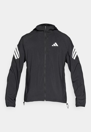 Chaqueta deportiva ligera negra con capucha, con detalles de tres rayas blancas en las mangas y cierre frontal con cremallera.