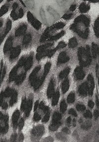 Schwarzer und grauer Leopardenmuster-Strickstoff mit V-Ausschnitt-Design. Weiche Textur und abwechslungsreiche Punktmuster überall.