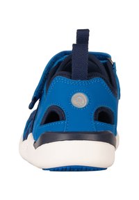 Chaussure de sport bleue avec une tige en mesh, semelle en caoutchouc, sangle Velcro et logo circulaire. Ouvertures sur les côtés pour la respirabilité et le confort.