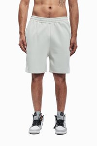 Világosszürke sportnadrág elasztikus derékrésszel, oldalzsebekkel és sima anyaggal, fekete-fehér magas szárú sportcipővel párosítva.