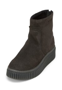 Botte de cheville en suède noir avec un bout rond, semelle en caoutchouc à rainures et accents de couture subtils sur le côté. Pas de matériel visible.