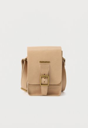 Geantă crossbody din piele bej, cu clapetă frontală, închidere cu cataramă din alamă, curea reglabilă și logo mic „Dr. Martens” deasupra cataramei.