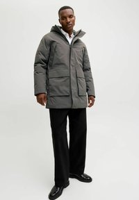 Hall gray isolatsiooniga jakk kapuutsi ja mitme eesoleva taskuga, millel on lukuga sulgemine. Loodud mugavaks sobituseks, pehme tekstuuriga, kantud valge särgi ja mustade pükstega.