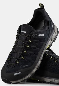 Černé turistické boty se svrškem z semiše a síťoviny, texturovanou podrážkou, vyztuženou špičkou, reflexními akcenty a zelenými detaily na tkaničkách.
