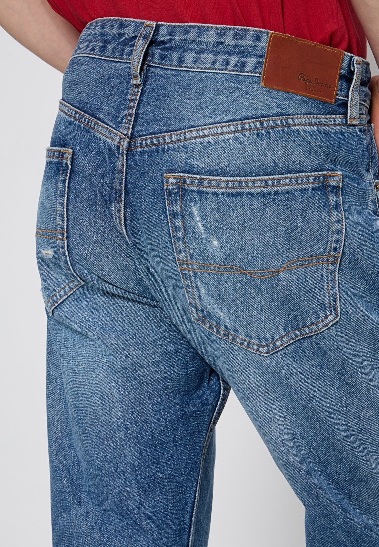 Hellblaue Jeans aus Denim mit hoher Taille, Gesäßtaschen und einem braunen Lederpatch mit dem Markennamen. An den Jeans sind abgenutzte Details sichtbar.