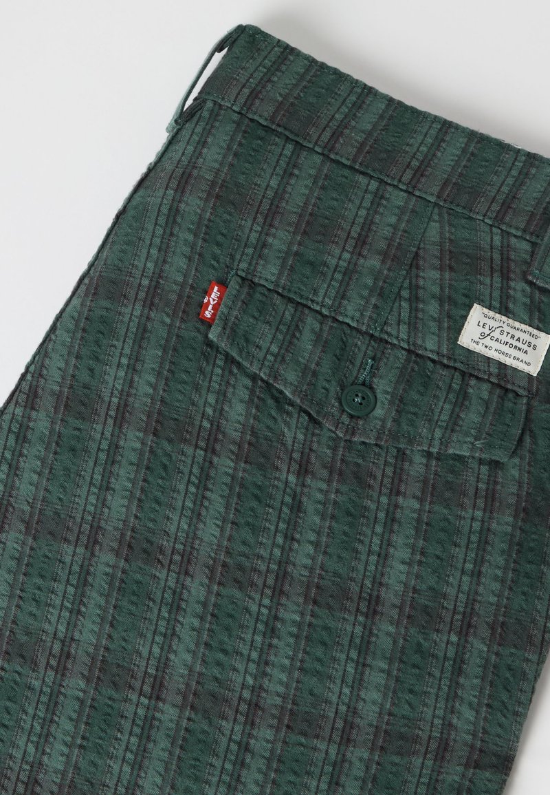 Tessuto a righe verdi e nere con tasca con bottoni, etichetta rossa Levi's e etichetta bianca del marchio Levi Strauss.