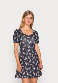 Vestido preto de manga curta com estampa de borboletas brancas, corpete ajustado, decote quadrado e saia rodada. Feito de um tecido leve com textura suave.