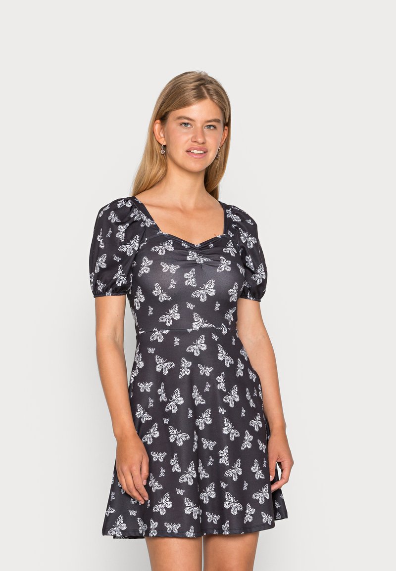 Vestido preto de manga curta com estampa de borboletas brancas, corpete ajustado, decote quadrado e saia rodada. Feito de um tecido leve com textura suave.