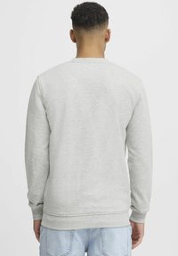Light grey sweatshirt made of cotton blend, featuring long sleeves, ribbed cuffs, and a round neckline. Smooth texture with minimal detailing.